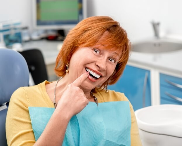 Smiling woman enjoying the benefits of dental implant supported dentures