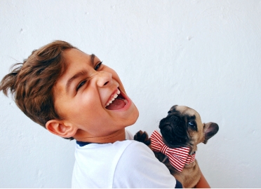 Young boy with puppy laughing after children's dentistry