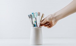 Hand reaches for toothbrush in holder