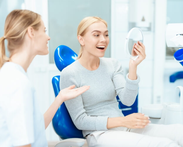 Woman looking at smile after choosing a great cosmetic dentist