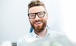 patient smiling while sitting in dental chair 