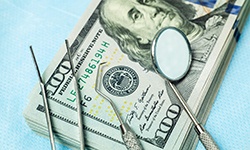 stack of money with dental tools