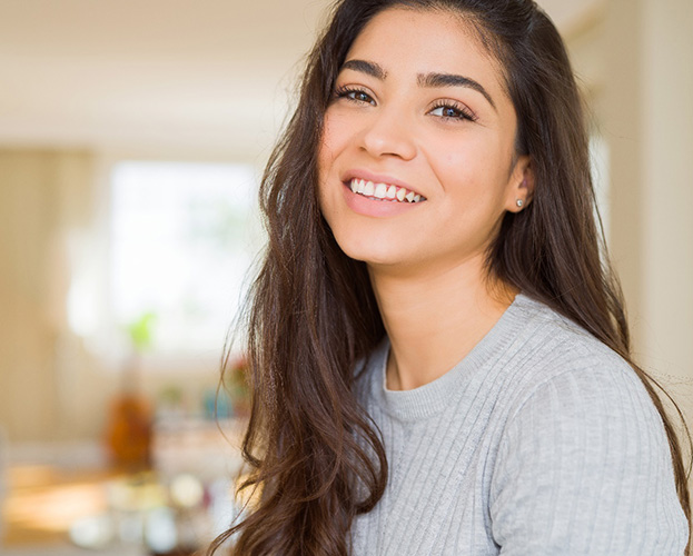Woman in grey shirt smiling while relaxing at home