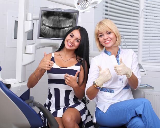 Dental team member and patient smiling together