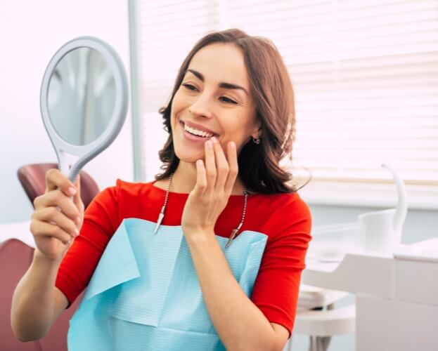 Woman looking at smile before emergency dentistry