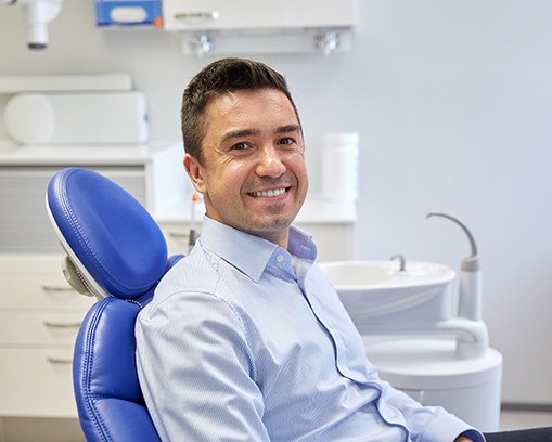 Man in button-up shirt sitting in dental chair and smiling