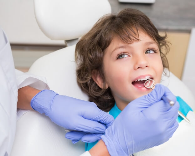 Dentist examining child's smile during healthy start treatment visit