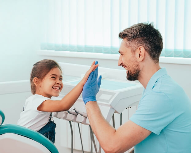 Dentist giving child a high five during healthy start treatment