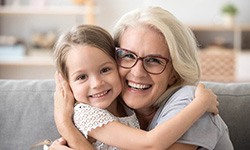 older woman smiling and hugging young girl after dental implants in Casper 