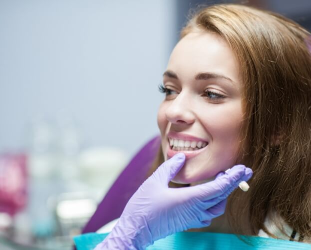 Dentist examining woman's smile after dental crown treatment