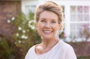 An older woman smiling outside.