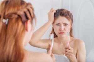 Concerned woman looking at toothbrush should see her Casper dentist