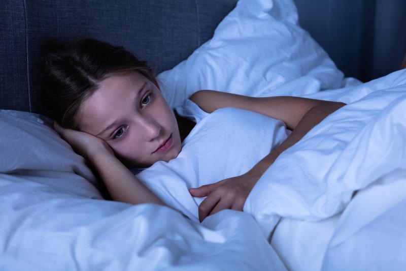 a little girl lying in bed awake in the middle of the night