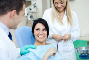 Male dentist, his assistant and female patient in dental practice