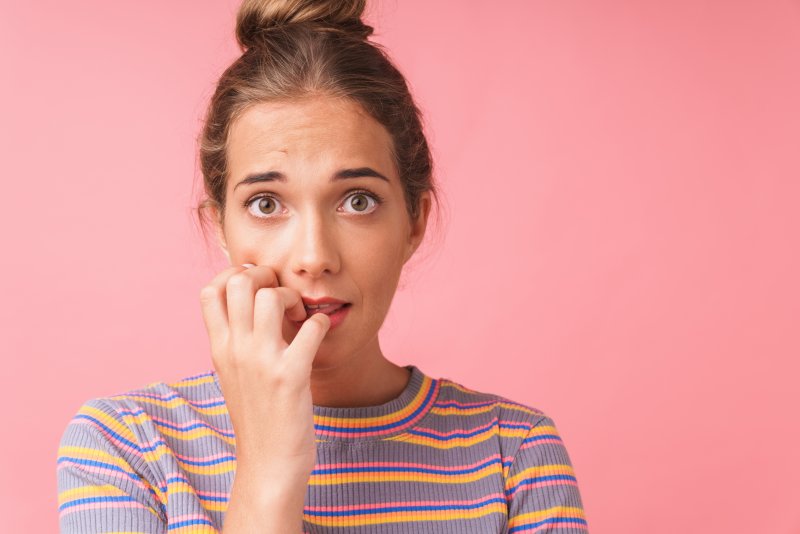 A nervous-looking woman biting her nails