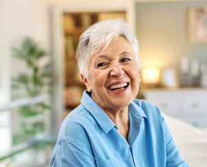 An older woman wearing dentures and smiling